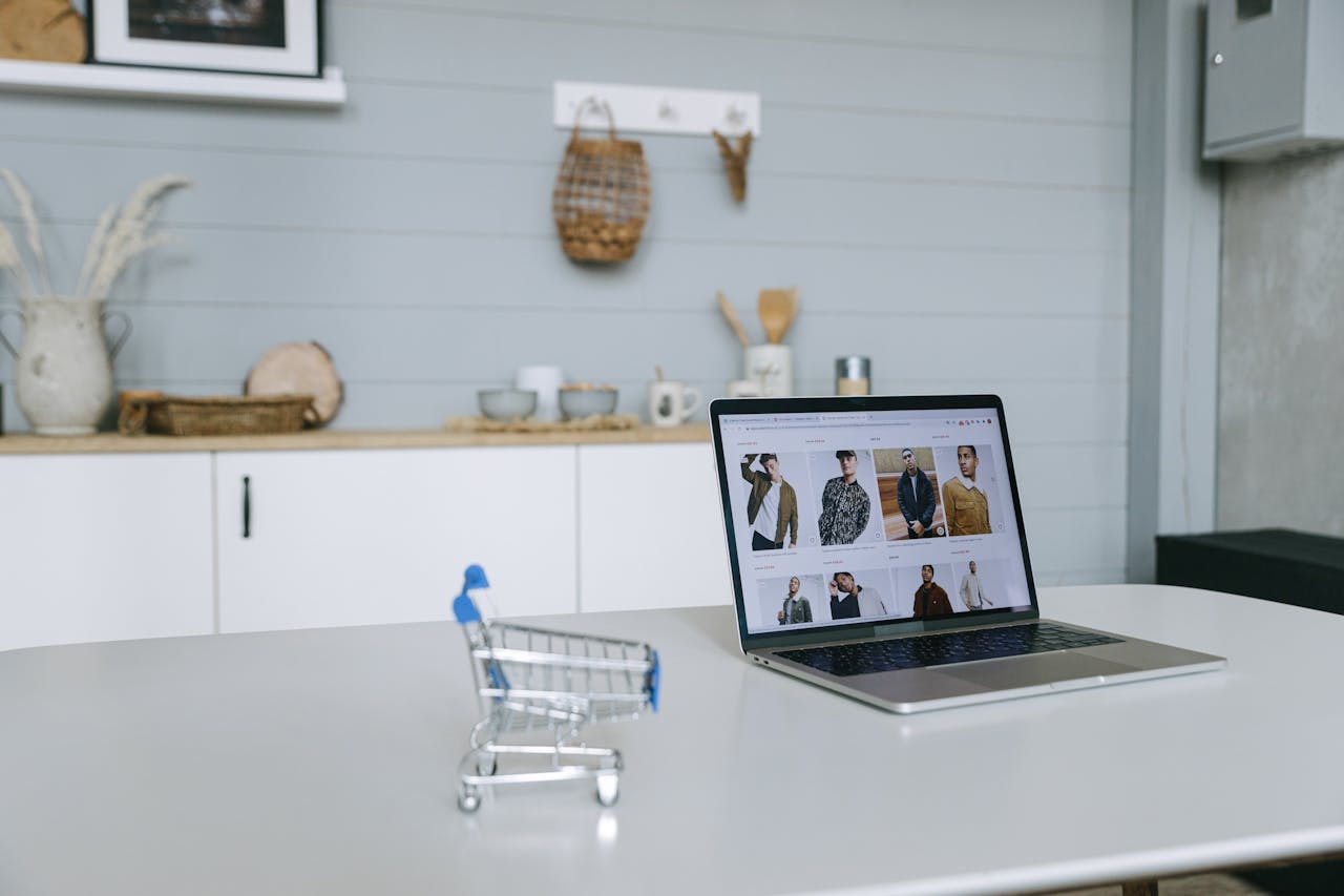 The Art of Drawing Readers In: Your attractive post title goes here A laptop displaying an online shopping portal sits on a minimal desk with a miniature shopping cart in focus.